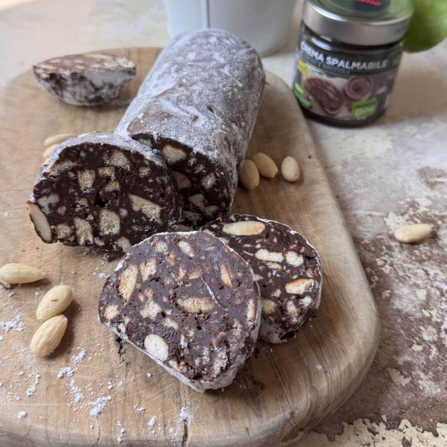 Salame di cioccolato vegano tagliato a fettine, decorato con zucchero a velo, pronto da servire come dolce facile e goloso