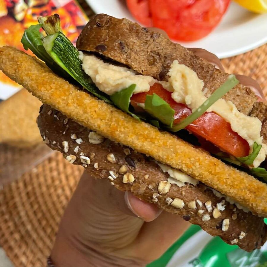 Panino estivo con hummus, cotoletta Vegamo, zucchine grigliate, pomodoro e rucola su pane rustico, un'opzione vegana fresca e gustosa