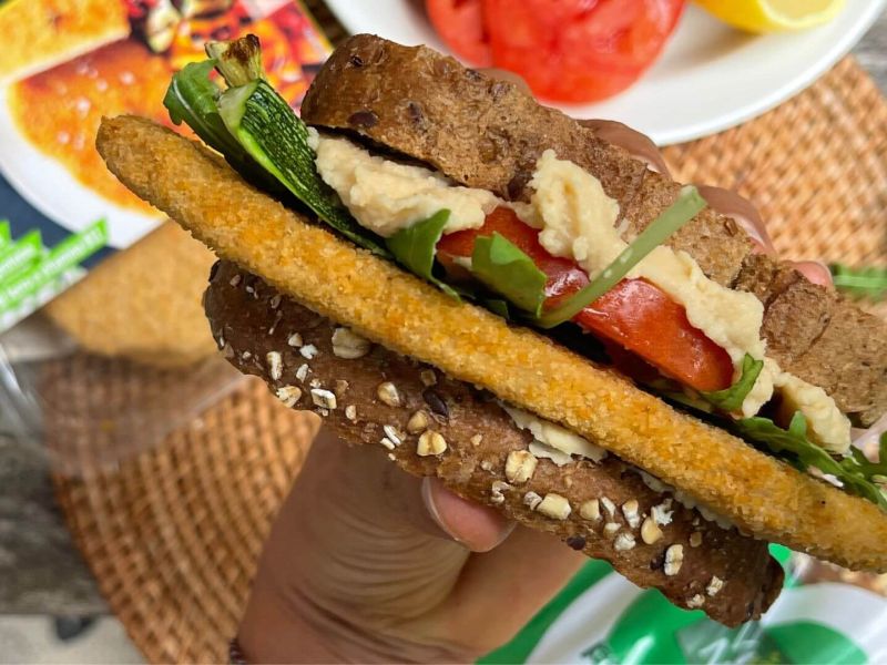 Panino estivo con hummus, cotoletta Vegamo, zucchine grigliate, pomodoro e rucola su pane rustico, un'opzione vegana fresca e gustosa