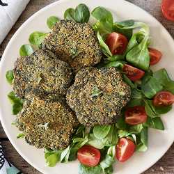 Piatto bianco con insalata, pomodori e burger di spinaci a forma di margherite