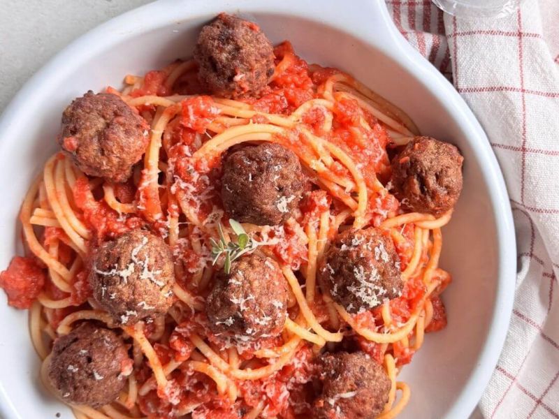 Piatto di spaghetti al pomodoro con polpettine vegetali Vegamo croccanti, serviti con sugo profumato all’origano e basilico, ricetta vegana ispirata a Lilli e il Vagabondo.