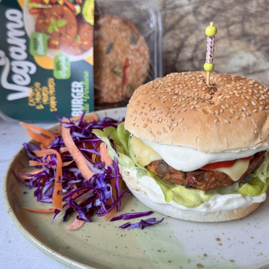 Burger vegano di verdure Vegamo con formaggio vegetale fuso, lattuga, pomodoro e maionese affumicata all’aglio, servito in panino con semi di sesamo.