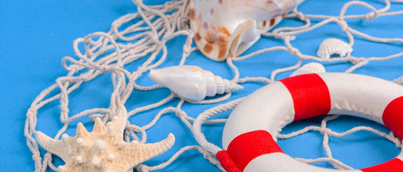 Decorazioni marine con conchiglie, stella marina, rete da pesca e salvagente bianco e rosso su sfondo azzurro